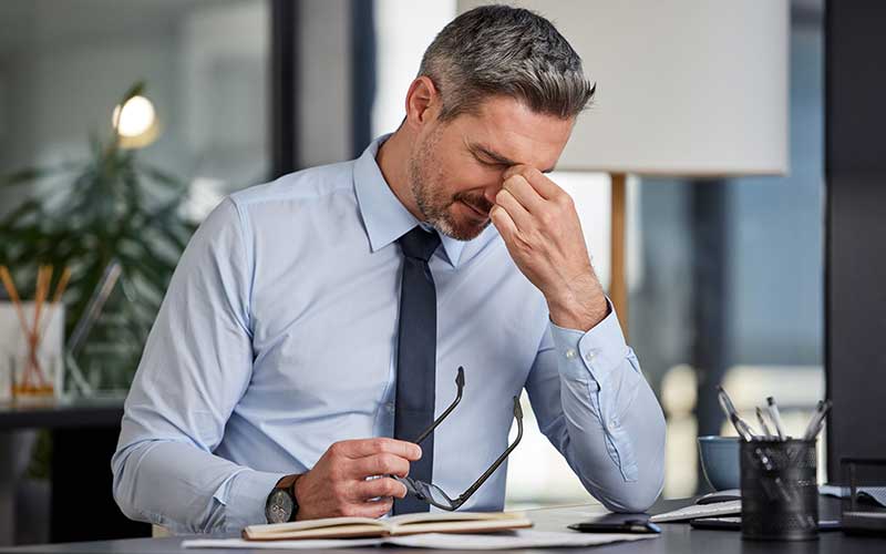 A businessman sits at his desk struggling to concentrate due to his depression.