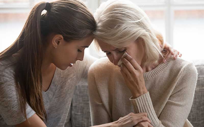 A woman tries to comfort another woman who is tearful.