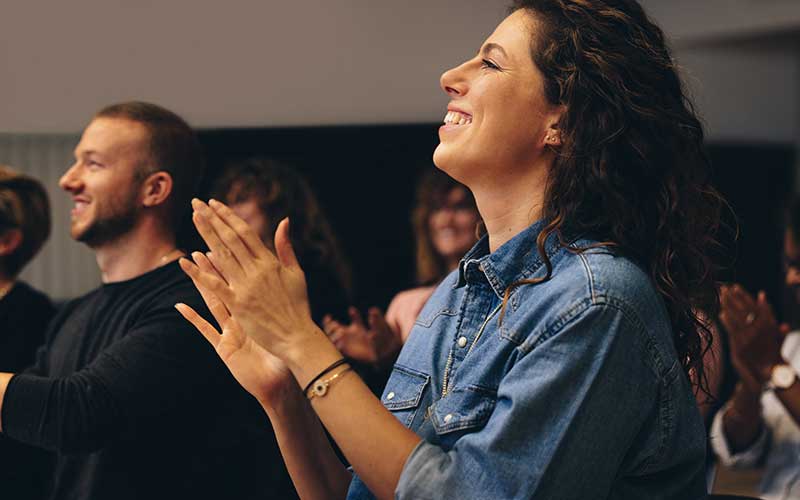 An engaged audience claps enthusiastically for the presentation they're attending.